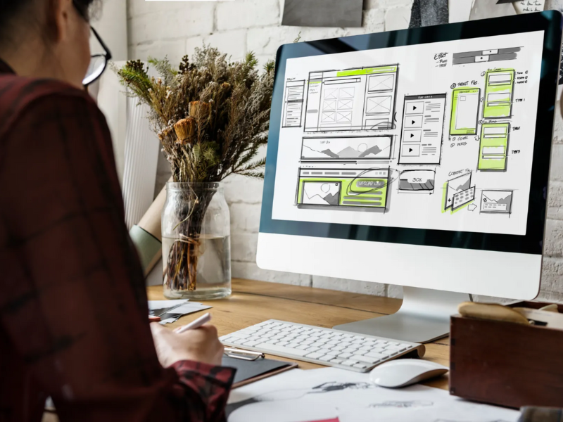 Designer travaillant sur la maquette d’une refonte site web avec wireframes affichés sur un écran